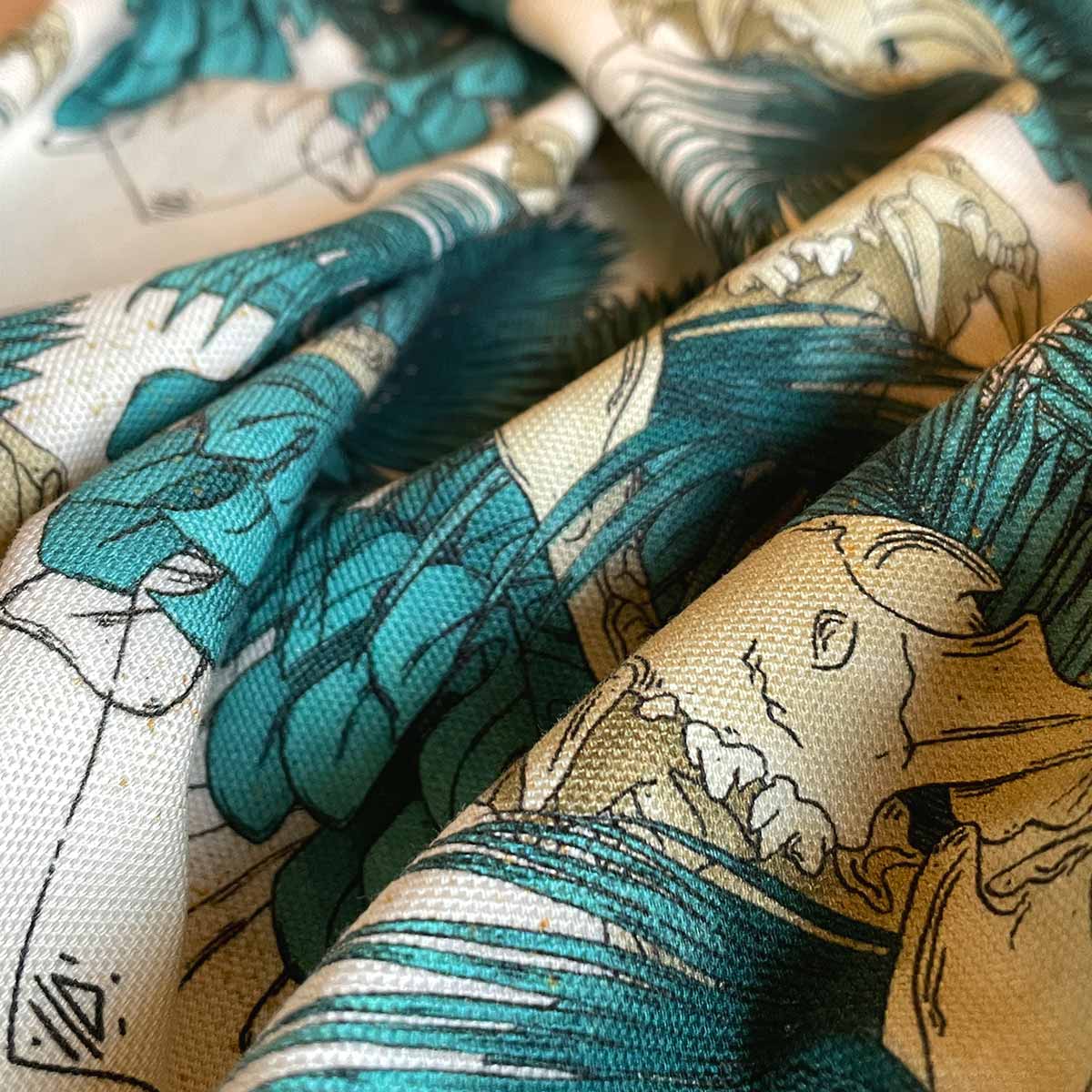 Close up of tea towel wrinkled fabric. Designs of tropical leaves in teal with lion skull open mouth