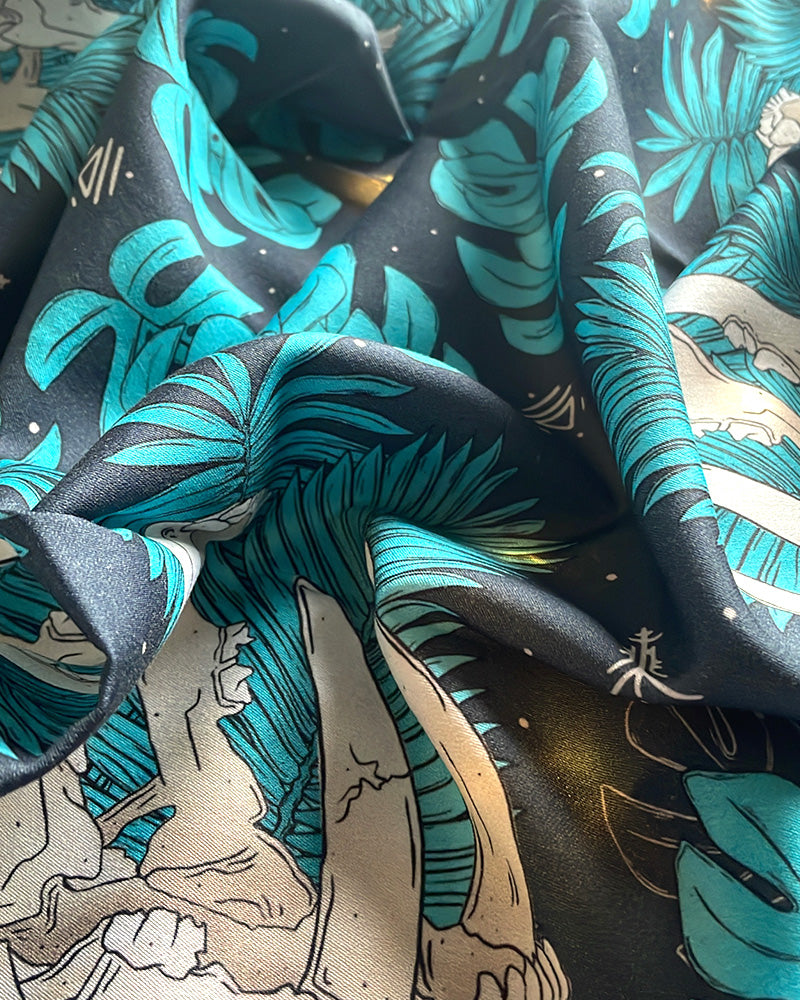 A close-up of draped dark fabric featuring a tropical print with turquoise palm leaves and monstera plants, rune icons and saber tooth tiger skull. exotic prints on bandanas