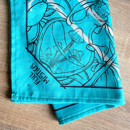 Folded turquoise bandana featuring a unique design with Earth, crystals, plants, and bones. Perfect for nature lovers, bohemian fashion, or occult enthusiasts. Illustrated. Mushrooms.