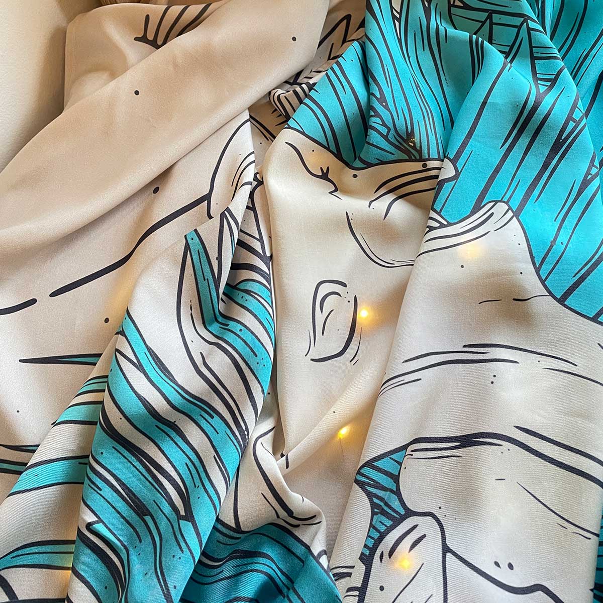 Crinkled fabric laid on table, top view, fairy lights under. Print of plants in teal, cream background, runes, animal fossil