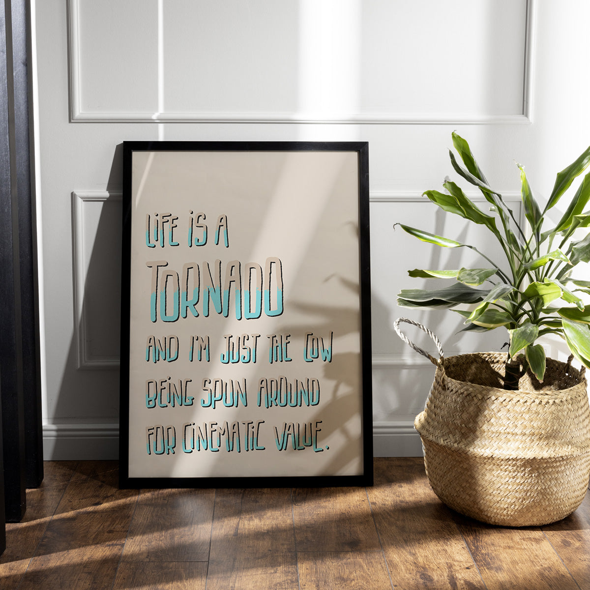 Art print framed sitting on wooden floor. Funny text about life in tall hand drawn letters in cream and turquoise light cream background