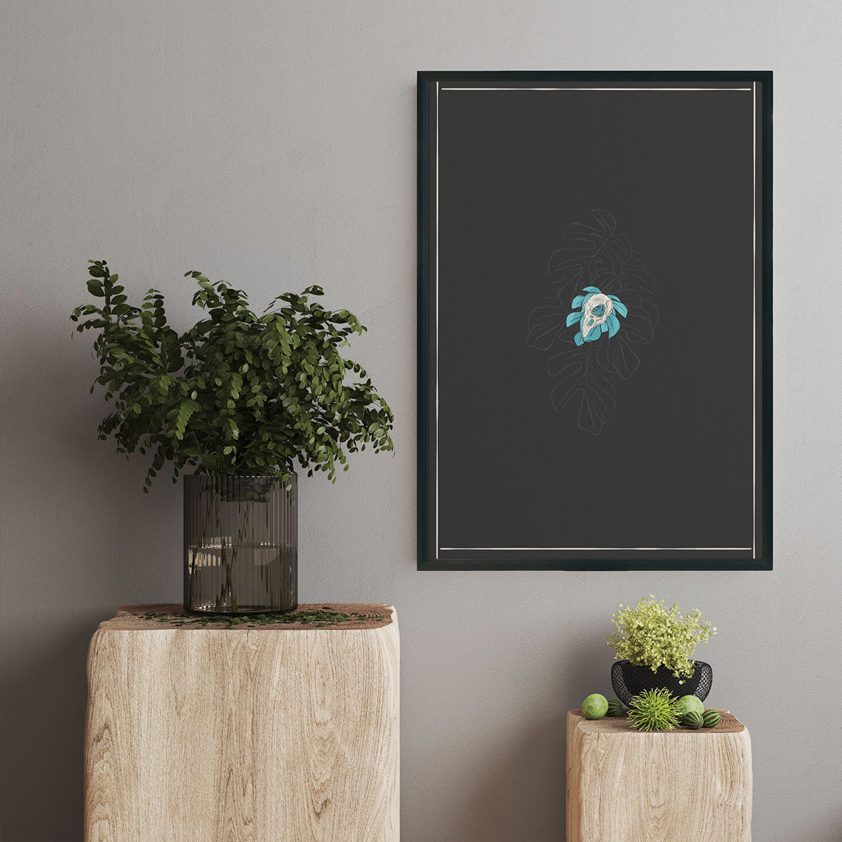 art print hanging above block of wood and plants sitting, design of single bird skull tiny monstera leaves behind, bigger outlined monstera leaves watermark in light grey merging with background in charcoal, thin cream lines as borders